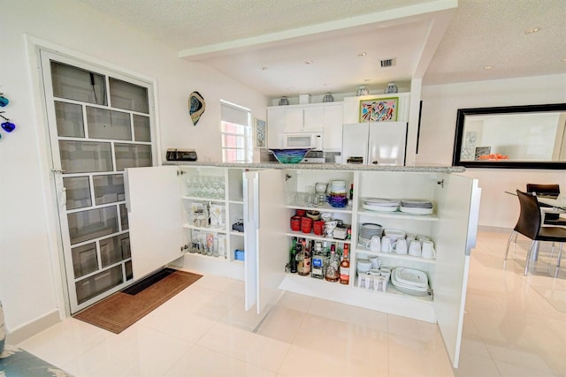 interior space with a textured ceiling and light tile patterned floors