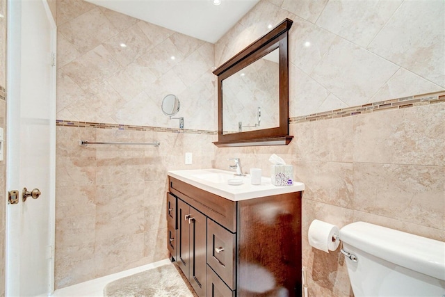 bathroom featuring vanity, tile walls, and toilet