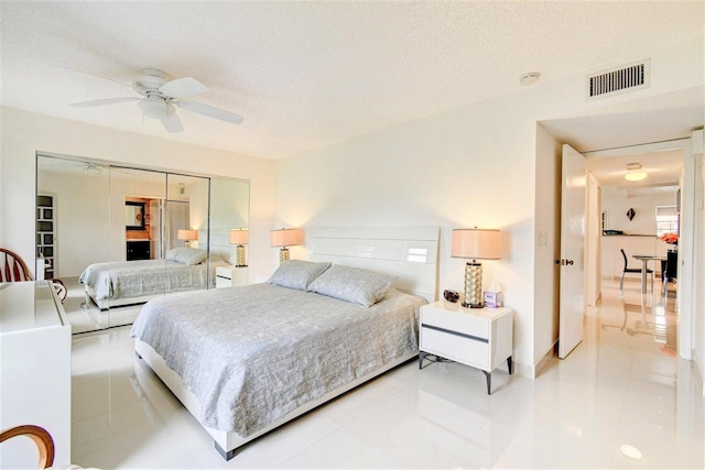 bedroom with a ceiling fan, visible vents, and a textured ceiling