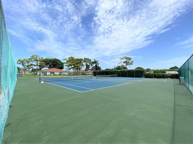 view of tennis court featuring community basketball court and fence