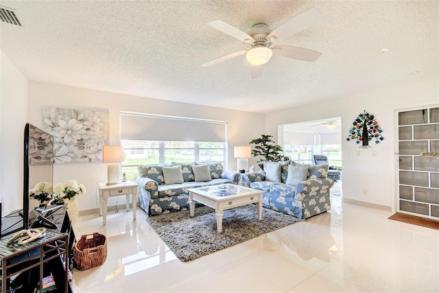 living room featuring a textured ceiling, ceiling fan, and tile patterned floors