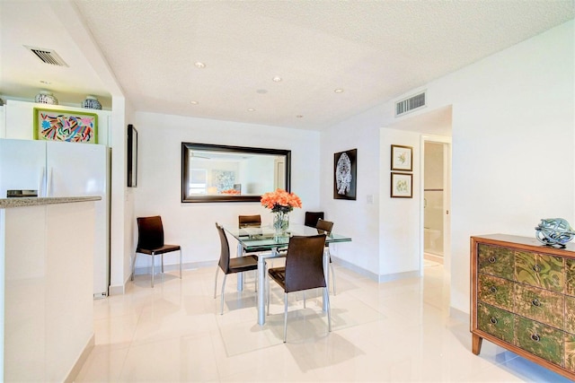 tiled dining space with a textured ceiling