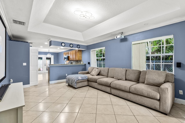 tiled living room featuring a tray ceiling, ornamental molding, and a textured ceiling