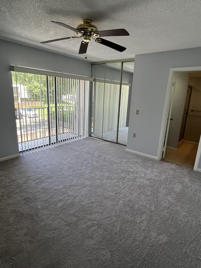 carpeted empty room featuring baseboards, a ceiling fan, and a textured ceiling