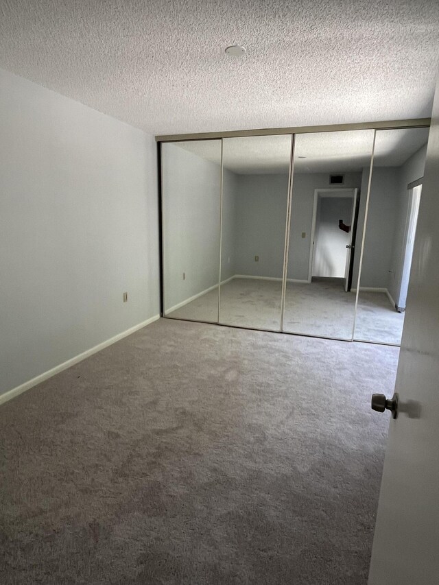 unfurnished bedroom featuring a closet, light colored carpet, and a textured ceiling