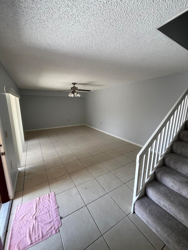 tiled empty room featuring a textured ceiling and ceiling fan