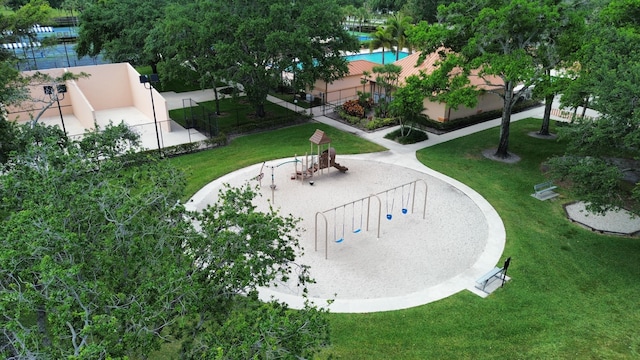 view of property's community with playground community, a lawn, and fence