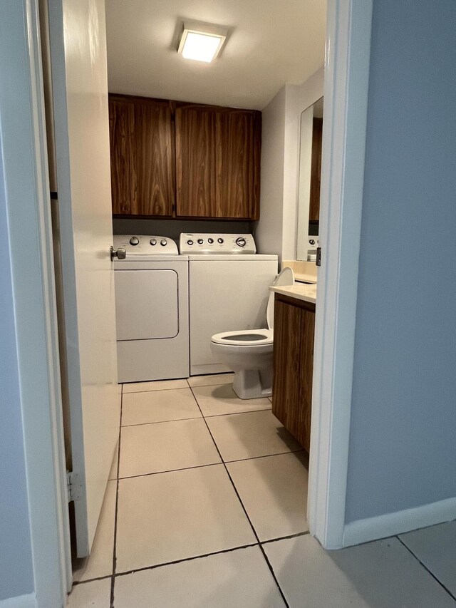 washroom with cabinets, washer and clothes dryer, and light tile patterned floors