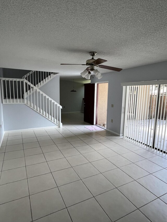 tiled empty room with ceiling fan and a textured ceiling