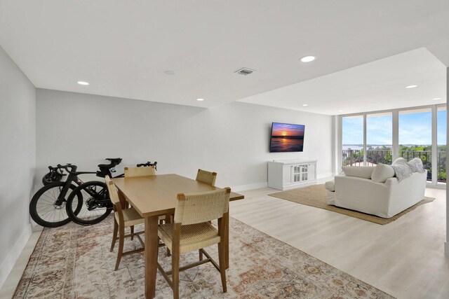 dining space with expansive windows and light hardwood / wood-style floors