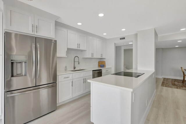 kitchen with light hardwood / wood-style flooring, appliances with stainless steel finishes, and white cabinets