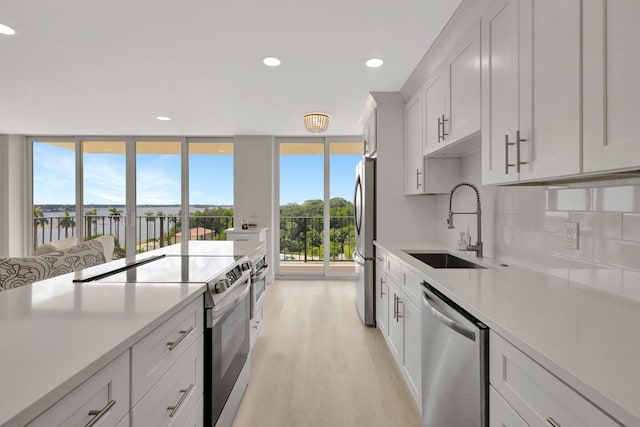 kitchen with plenty of natural light, stainless steel appliances, white cabinets, and light hardwood / wood-style floors