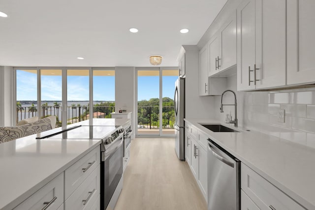 1801 S Flagler Dr Unit 701, West Palm Beach, FL 33401 - kitchen featuring appliances with stainless steel finishes, light countertops, light wood-style floors, white cabinetry, and a sink