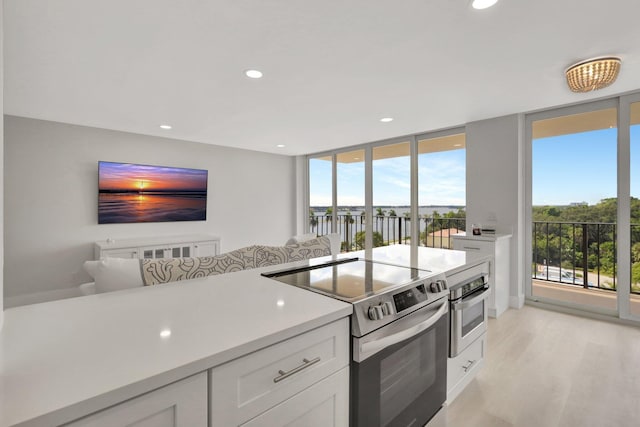 1801 S Flagler Dr Unit 701, West Palm Beach, FL 33401 - kitchen with light wood finished floors, appliances with stainless steel finishes, open floor plan, light countertops, and white cabinetry