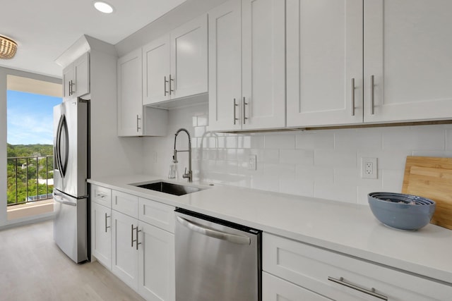 kitchen with appliances with stainless steel finishes, sink, decorative backsplash, and light hardwood / wood-style floors