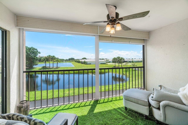 sunroom with ceiling fan and a water view