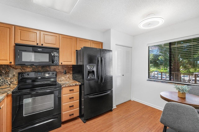 kitchen featuring a textured ceiling, black appliances, tasteful backsplash, dark stone countertops, and light wood-type flooring