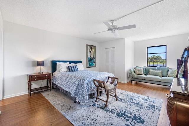 bedroom with a textured ceiling, ceiling fan, a closet, and wood-type flooring