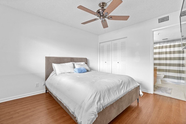 bedroom with ensuite bath, light wood-type flooring, a closet, ceiling fan, and a textured ceiling