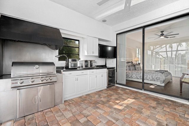 kitchen with ceiling fan, wine cooler, a textured ceiling, and white cabinetry