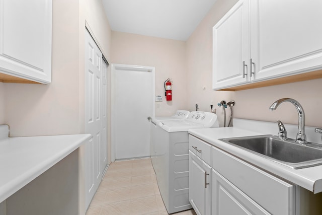 clothes washing area with light tile patterned floors, separate washer and dryer, cabinets, and sink