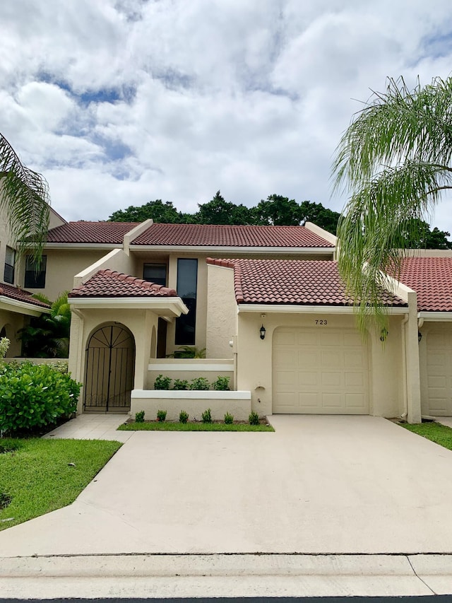 mediterranean / spanish-style house featuring driveway, a tile roof, an attached garage, and stucco siding