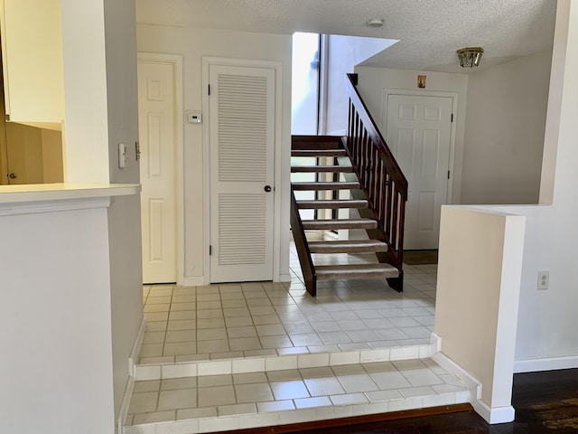 stairway featuring a textured ceiling and baseboards