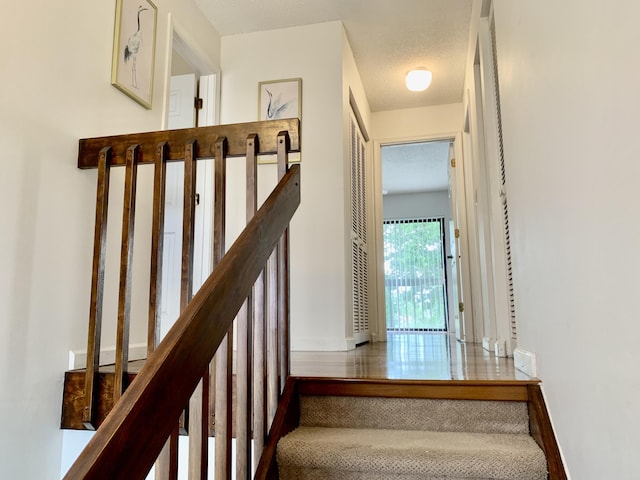 staircase featuring a textured ceiling and baseboards