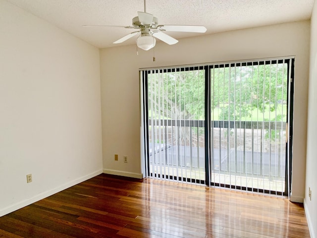 unfurnished room with dark wood-style floors, ceiling fan, a textured ceiling, and baseboards