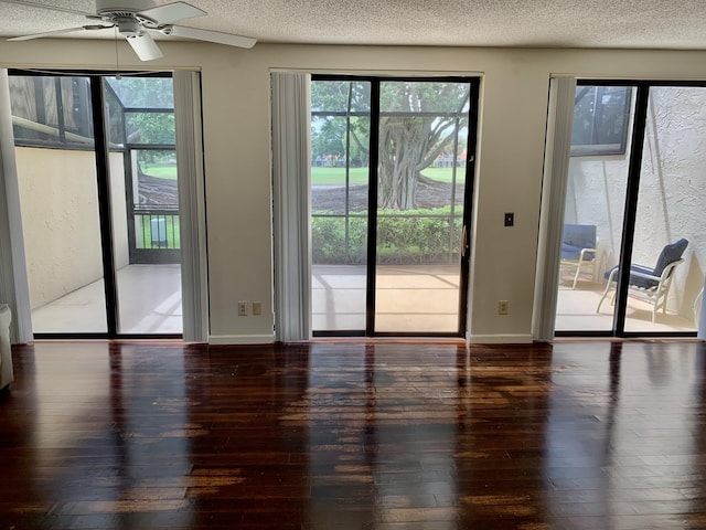 doorway to outside featuring dark wood-style floors, a wealth of natural light, a textured ceiling, and baseboards