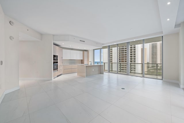 unfurnished living room with a wall of windows and light tile patterned flooring