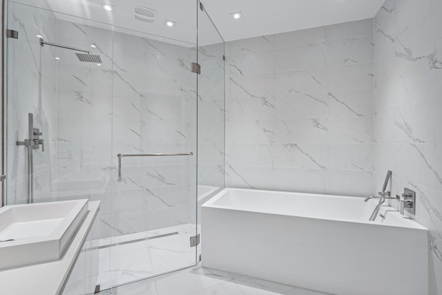 bathroom featuring plus walk in shower, tile walls, and vanity