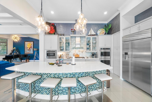 kitchen with a breakfast bar area, wall chimney range hood, hanging light fixtures, and appliances with stainless steel finishes