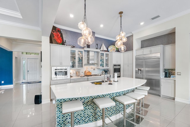 kitchen with stainless steel appliances, wall chimney range hood, light tile patterned floors, a large island, and a breakfast bar area