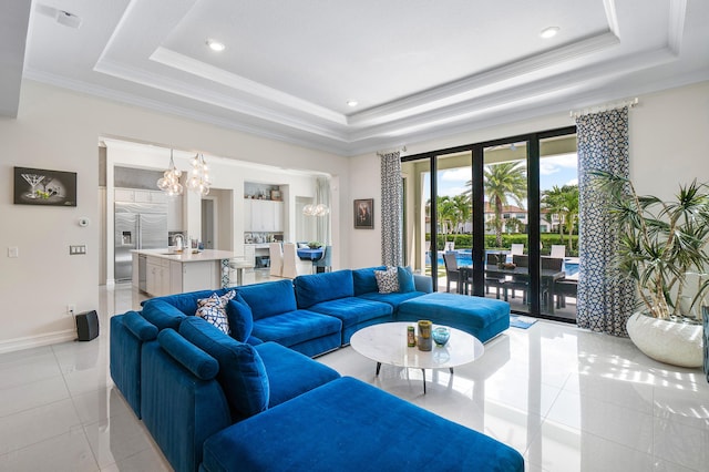 tiled living room featuring sink, crown molding, a raised ceiling, and a chandelier