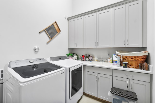 laundry room featuring sink, washer and dryer, and cabinets