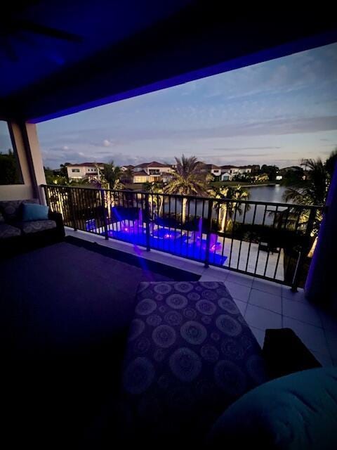 balcony at dusk featuring a water view