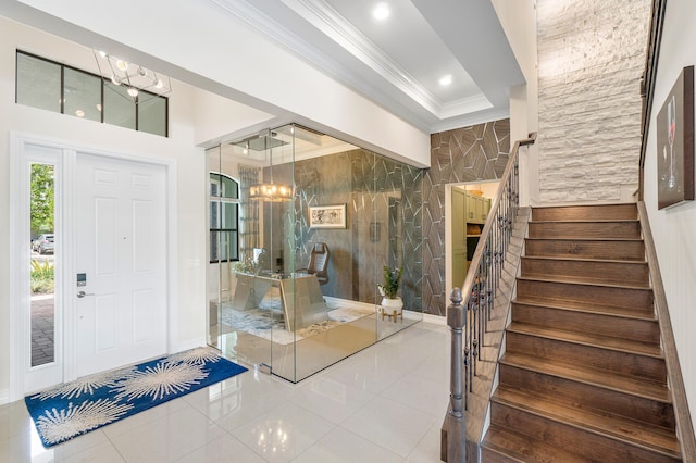 tiled foyer featuring a chandelier and crown molding