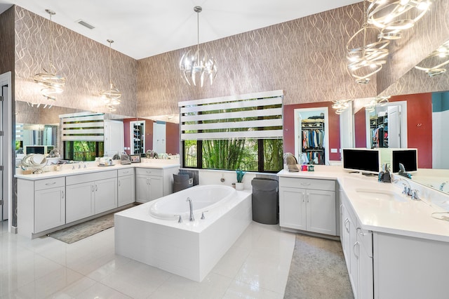 bathroom with tiled bath, tile patterned floors, a chandelier, and vanity