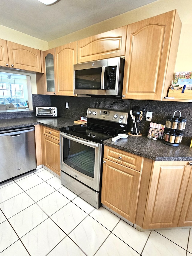 kitchen featuring light brown cabinetry, appliances with stainless steel finishes, and tasteful backsplash