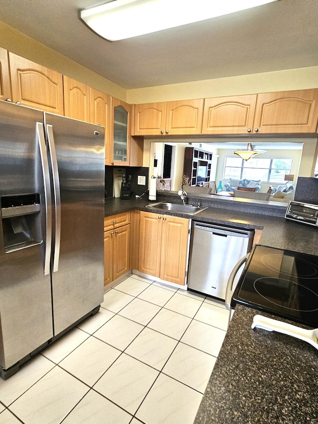 kitchen featuring appliances with stainless steel finishes, light tile patterned floors, light brown cabinetry, and sink