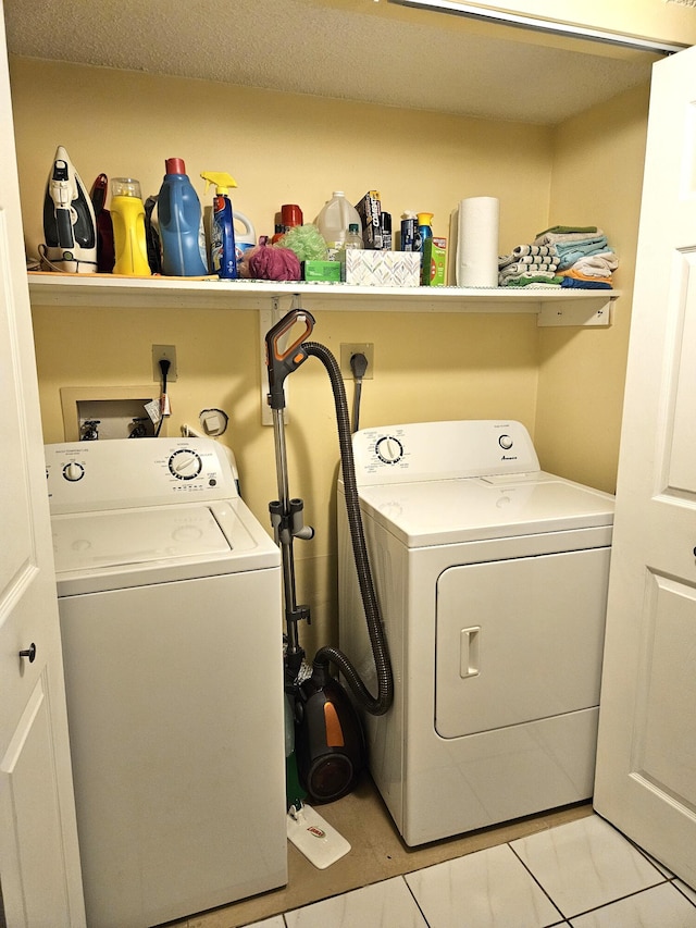 laundry area with washing machine and clothes dryer, a textured ceiling, and light tile patterned flooring