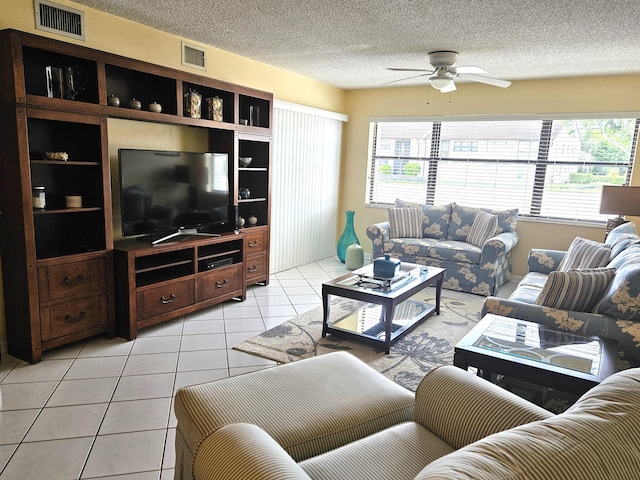 living room with a textured ceiling, ceiling fan, and light tile patterned floors