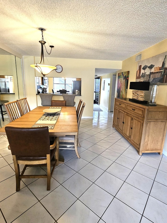 dining area with a textured ceiling and light tile patterned floors