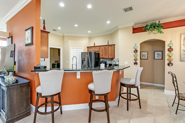 kitchen with a kitchen breakfast bar, kitchen peninsula, stainless steel fridge with ice dispenser, and crown molding