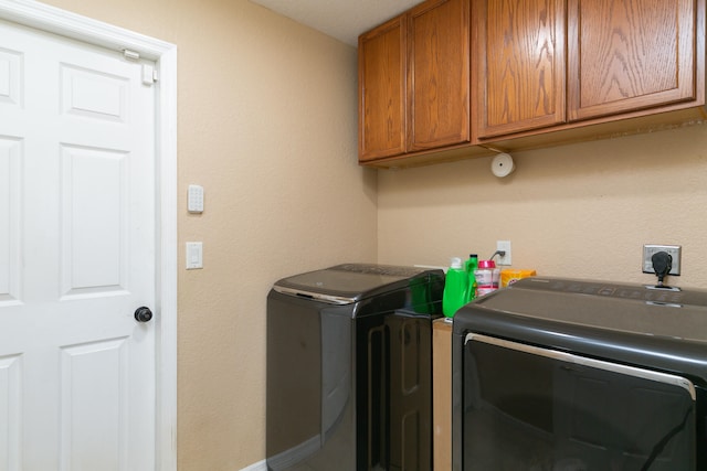 clothes washing area with washing machine and dryer and cabinets