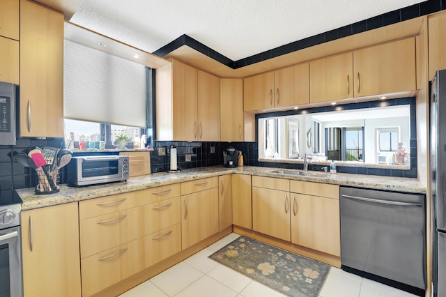 kitchen with light stone counters, backsplash, stainless steel appliances, and sink