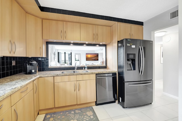 kitchen featuring light tile patterned floors, stainless steel appliances, light stone counters, sink, and decorative backsplash