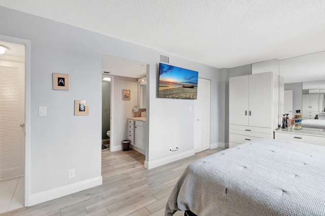 bedroom with light hardwood / wood-style flooring, connected bathroom, and a textured ceiling