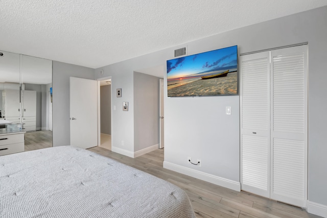 unfurnished bedroom with a textured ceiling, a closet, and light hardwood / wood-style floors